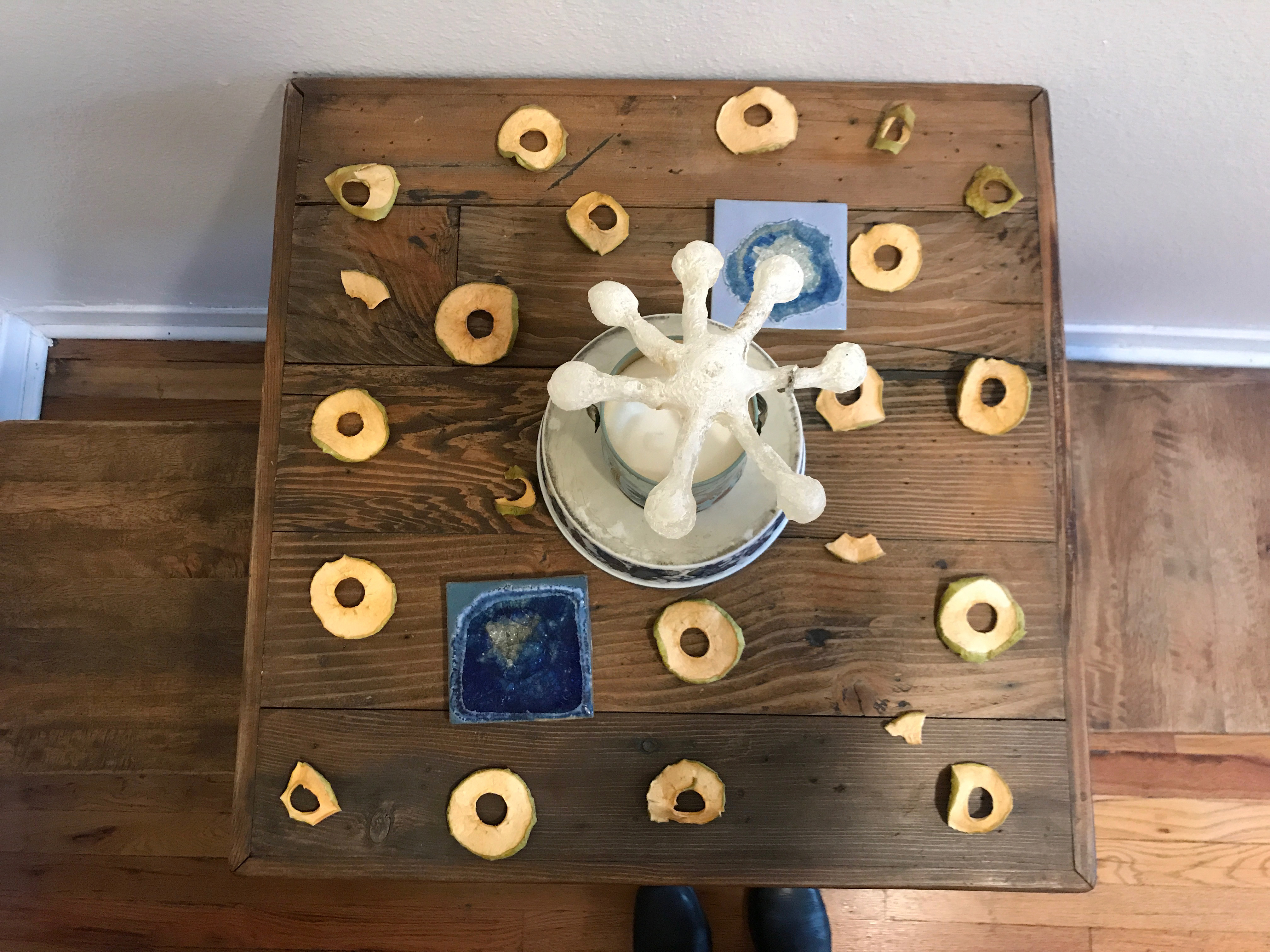 Ariel view of a sugar sculpture in an asterisk shape surrounded by dried apple peels on a table